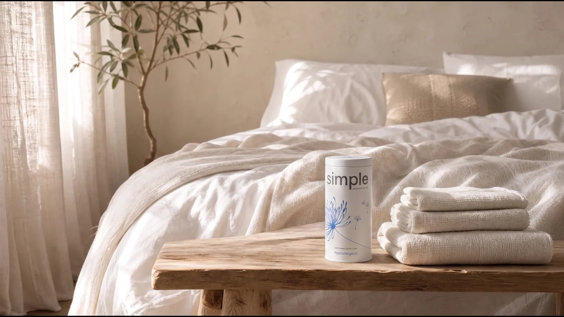 A simple tin beside folded towels in a sunlit bedroom